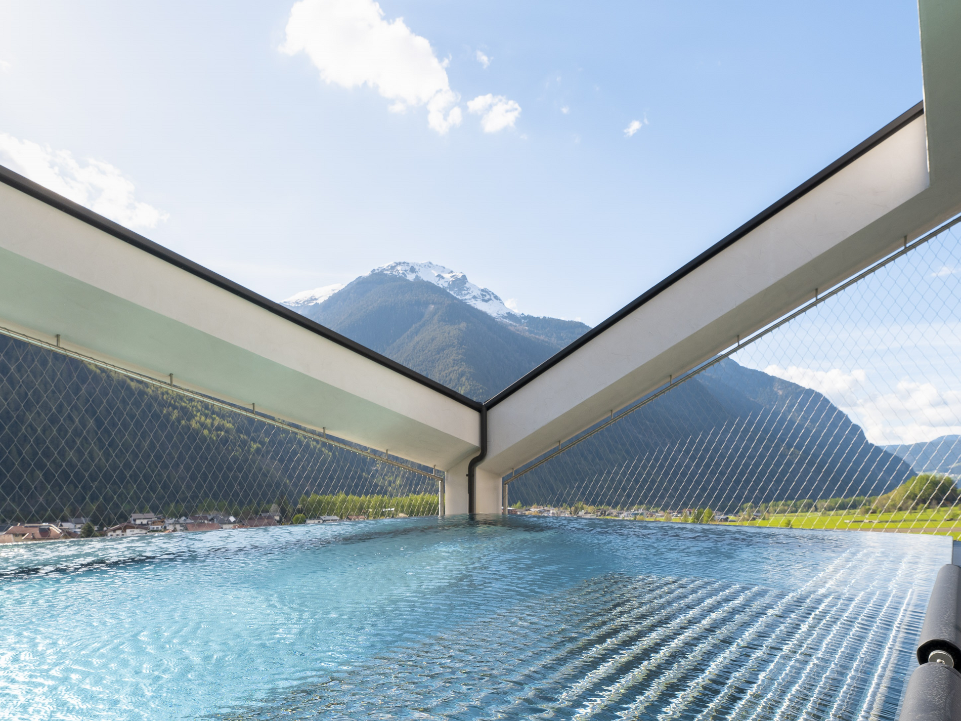 Pool des LifeSteil Appartementresort mit klarem Wasser vor alpiner Kulisse mit Bergen und Himmel im Hintergrund.